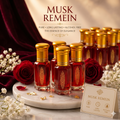 Musk Remein perfume bottles with gold caps on a marble surface with roses and flowers.